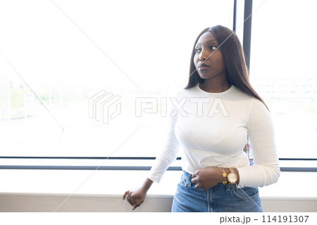 Confident Young Black Woman Posing by Window with Urban Background 114191307