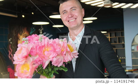 Businessman in suit with snow-white smile holds bouquet 114191746