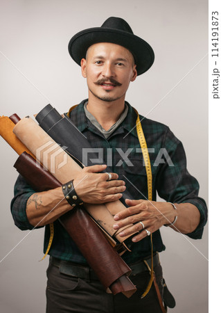 Artisan of leather in creative black hat posing with leather goods in studio. 114191873