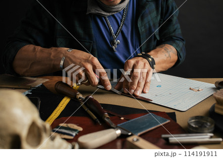 Leather goods master and handmade leather wallets. Workflow in the workshop. 114191911