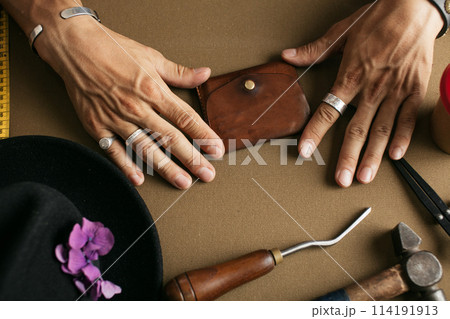 Leather goods master and handmade leather wallets. Workflow in the workshop. Leather goods master and handmade leather wallets. Workflow in the workshop. 114191913
