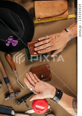 Leather goods master and handmade leather wallets. Workflow in the workshop. Leather goods master and handmade leather wallets. Workflow in the workshop. 114191914