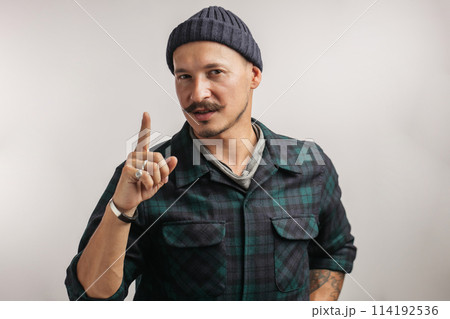 Confident man in knitted hat pointing finger upwards over white background. 114192536