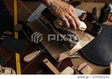 Care for leather shoes, close up of cropped shoemaker hands rubbing up boots Care for leather shoes, close up of cropped shoemaker hands rubbing up boots 114193232