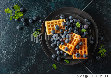 Belgian waffles with blueberries on a black plate. 114194011
