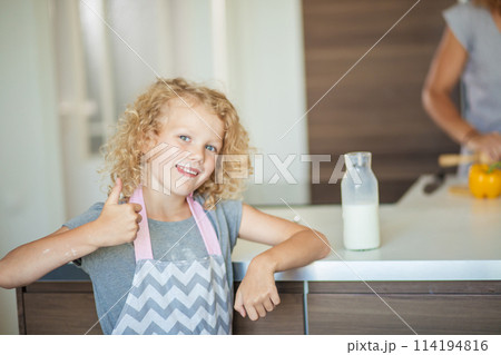 Cute little girl with fair frizzy hair drinking a glass of milk in kitchen Cute little girl with fair frizzy hair drinking a glass of milk in kitchen 114194816