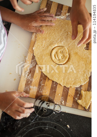 Child and women cutting form for cookie in dough. Happy family and childhood. 114194835