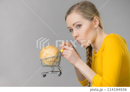 Woman holding shopping cart with bread Woman holding shopping cart with bread 114194936