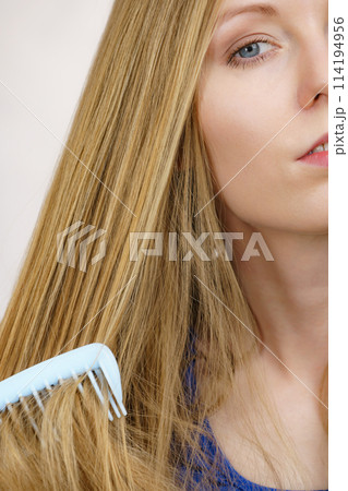 Woman combing long healthy blonde hair 114194956