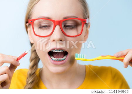Woman smiling cleaning teeth with braces 114194963