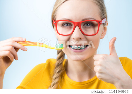 Woman smiling cleaning teeth with braces Woman smiling cleaning teeth with braces 114194965