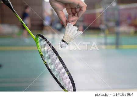 The badminton player holding a white shuttlecock and racket 114195964