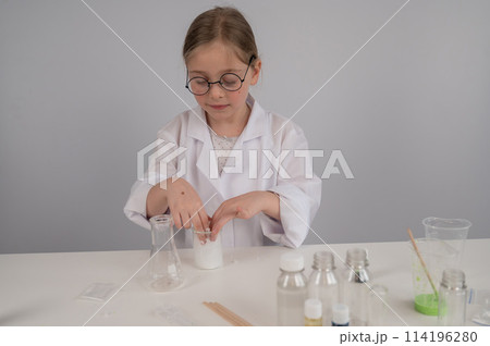 A Caucasian girl in glasses and a white coat does chemical experiments on a white background. A Caucasian girl in glasses and a white coat does chemical experiments on a white background. 114196280