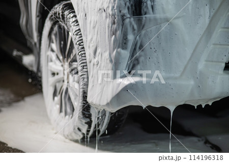 Foam drips from the bumper of a black car. Car wash.  114196318