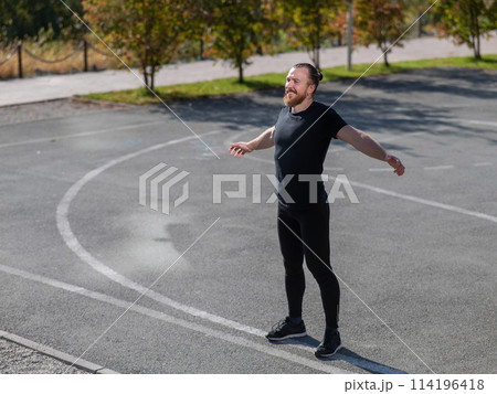 Bearded man doing exercises outdoors.  114196418