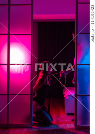 A woman is kneeling in front of a man. BDSM sex concept. Vertical photo.  114196422