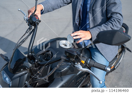 A man opened the charging socket on an electric motorcycle. 114196460