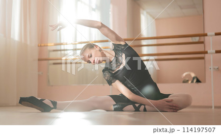 Woman in pointe shoes sits on the floor and does ballet warm-up. Woman in pointe shoes sits on the floor and does ballet warm-up. 114197507