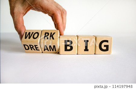 Work or dream big symbol. Businessman turns wooden cubes, changes words 'dream big' to 'work big'. Beautiful white table, white background, copy space. Business and dream or work big concept. 114197948