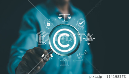 Digital copyright or patent concept. Author rights and patented intellectual property. Businessman holding a magnifying glass focuses on a copyright symbol surrounded by legal icons. trademark license 114198378