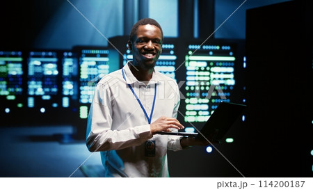 Technician making sure high tech facility data servers are appropriately equipped to provide redundancy, automatic failover and rapid reconfiguration of clusters to minimize failure of individual rigs 114200187