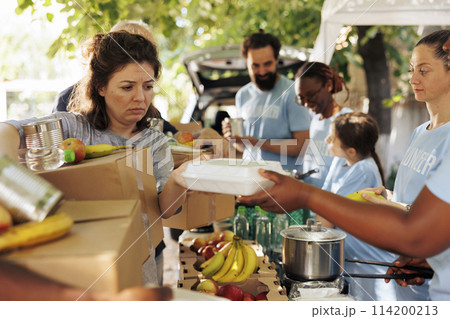 Multiracial group offers assistance by distributing food to the poor and needy. Volunteers of different ethnicities join together to aid homeless people by participating in humanitarian food drive. 114200213