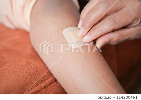 applying adhesive bandage on a child feet  114200461