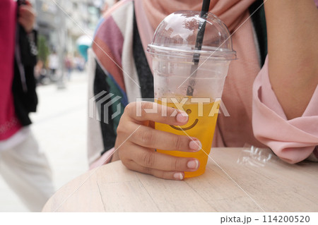 orange juice with ice cube in a plastic container  114200520