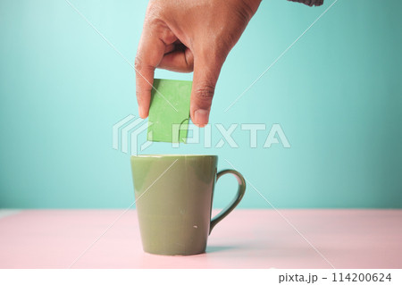 young man putting artificial sweetener in tea, 114200624