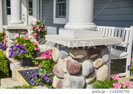 Sunny Residential Entrance with Stone Column and Flower Arrangements 114200792