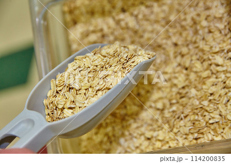Scoop of Rolled Oats in Health Food Store Setting Close-Up 114200835