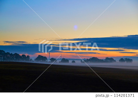 Misty Sunrise with Wind Turbines in Rural Landscape 114201371