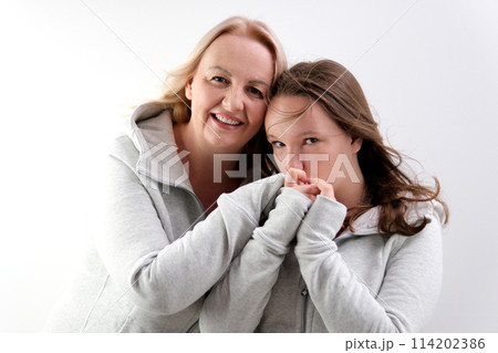 love of daughter and mother hugging kisses tenderness girl kisses her mother's hands mother hugs kisses her daughter on the cheek two women on a light background a lot of tenderness and joy of love love of daughter and mother hugging kisses tenderness girl kisses her mother's hands mother hugs kisses her daughter on the cheek two women on a light background a lot of tenderness and joy of love 114202386