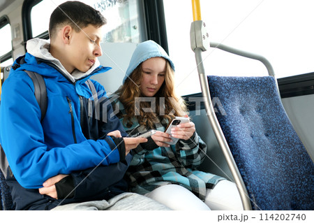 two teenagers in blue clothes sit on a bus Canada Vancouver hoods autumn winter spring tracksuits use a mobile phone search for geolocation travel travelers real life two teenagers in blue clothes sit on a bus Canada Vancouver hoods autumn winter spring tracksuits use a mobile phone search for geolocation travel travelers real life 114202740