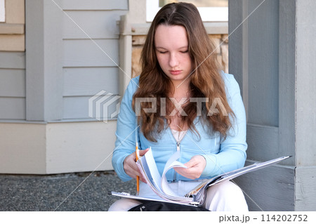 young girl teenager sits on porch in hands with a folder, a magazine and pencil, do homework, solve problems, wait at the door, a beautiful woman, young white jeans, a briefcase, think, work, study young girl teenager sits on porch in hands with a folder, a magazine and pencil, do homework, solve problems, wait at the door, a beautiful woman, young white jeans, a briefcase, think, work, study 114202752