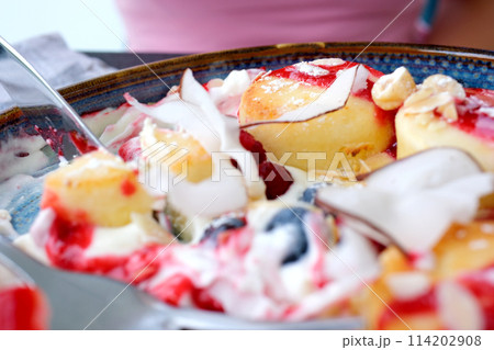 Cottage cheese fritters Syrniki served with fresh berries and honey, small baked cheesecakes. Taking bite with a fork. Breakfast or lunch footage 114202908