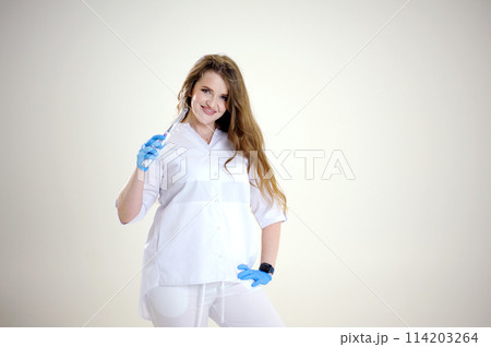 Photopolymer lamp Beautiful female doctor with a lamp in her hands smiling in a white suit on a white background studio photo advertising dental office space for text banner billboard Photopolymer lamp Beautiful female doctor with a lamp in her hands smiling in a white suit on a white background studio photo advertising dental office space for text banner billboard 114203264