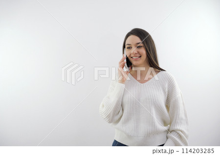Beautiful young girl speaking on phone with client while sitting on sofa in modern office. Modern business woman concept. 114203285