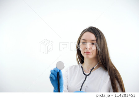 Beautiful young African American nurse or doctor with stethoscope stands, looking to the right side wearing blue scrubs and long curly hair Beautiful young African American nurse or doctor with stethoscope stands, looking to the right side wearing blue scrubs and long curly hair 114203453