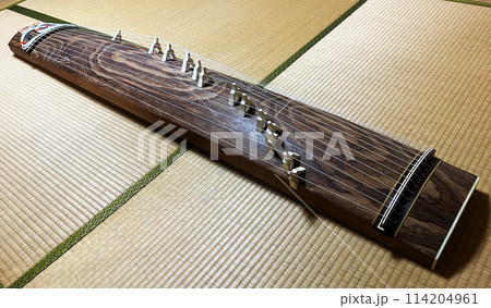 日本の和室の畳の上に伝統的な13本の弦楽器である琴柱付きの箏がある。全体像 日本の和室の畳の上に伝統的な13本の弦楽器である琴柱付きの箏がある。全体像 114204961