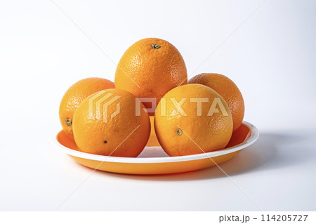 Fresh oranges on a plate isolated on a white background. Fresh oranges on a plate isolated on a white background. 114205727