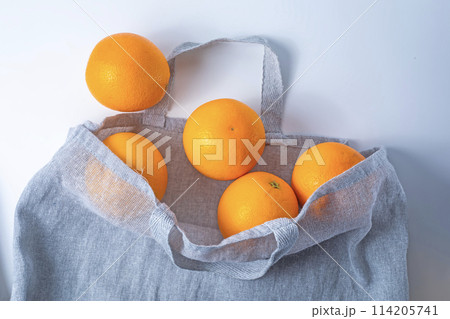 Fresh ripe oranges in a reusable shopping bag on a white background. 114205741