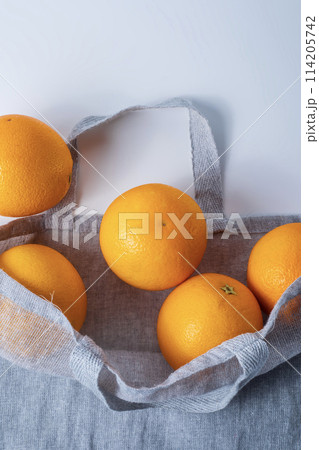 Fresh oranges in a textile shopping bag on a white background. 114205742