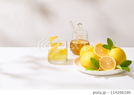 A round dish of fresh lemon placed next a honey jar and a glass of lemon juice on the right side of photo. The left side is blank for presentation or adding text 114206190