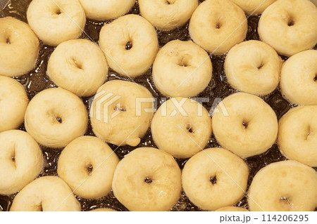 Mini donuts are fried in a pan with very hot oil. 114206295