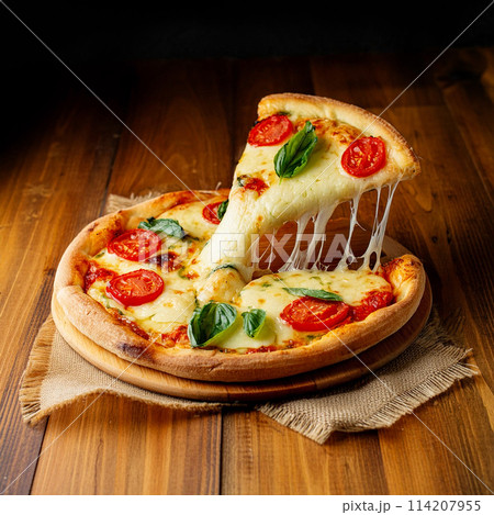 一枚のカットを持ち上げたピザ・マルゲリータ　木製テーブルの背景 114207955