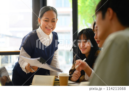 Friendly middle age lecturer assisting students in classroom. Education concept 114211088