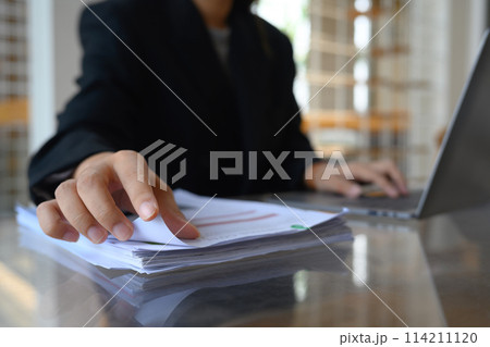 Cropped shot male entrepreneur reading document at office desk Cropped shot male entrepreneur reading document at office desk 114211120