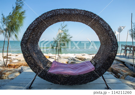 The wooden seat is shaped like a bird's nest with a beautiful sea view. 114211260