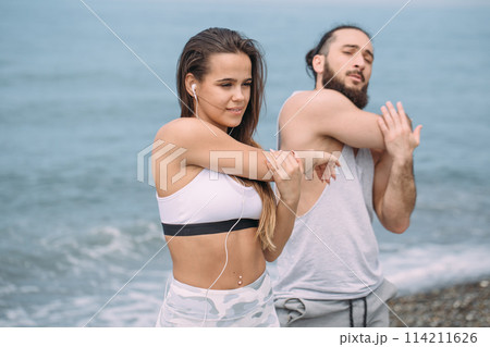 Couple stretching on beach 114211626